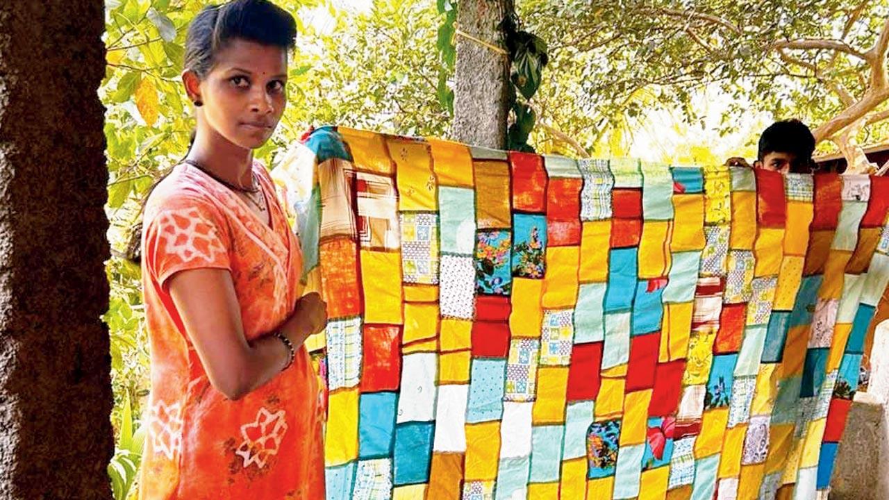 A woman from the foundation holds up a hand-crafted quilt 