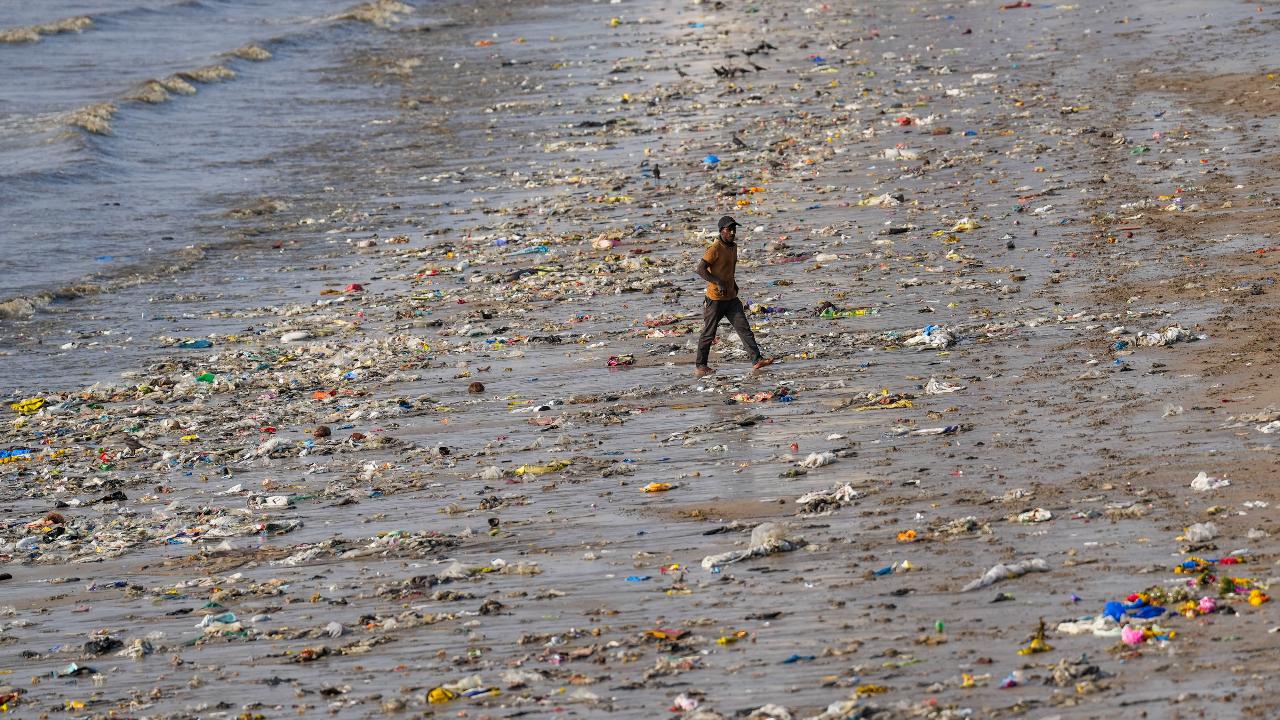 A boy walks on a beach littered with plastic and other waste materials, on Earth Day in Mumbai, Monday, April 22, 2024 (PTI Photo/Kunal Patil)