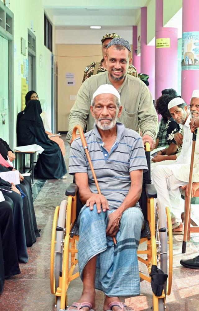 A man assists an elderly voter as he arrives to cast her vote during phase-I of voting for the Lok Sabha elections, in Lakshadweep on Friday. (ANI Photo)