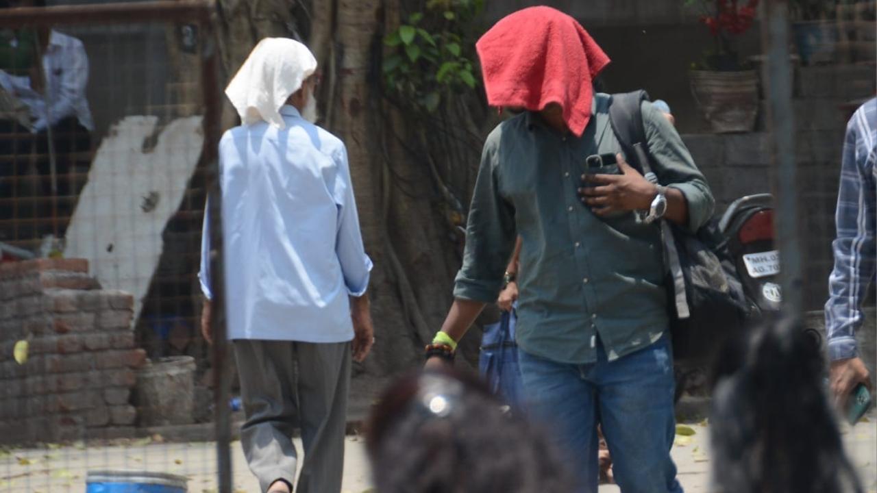 People were seen protecting themselves from heat on Tuesday afternoon. Pics/Atul Kamble and Sameer Abedi