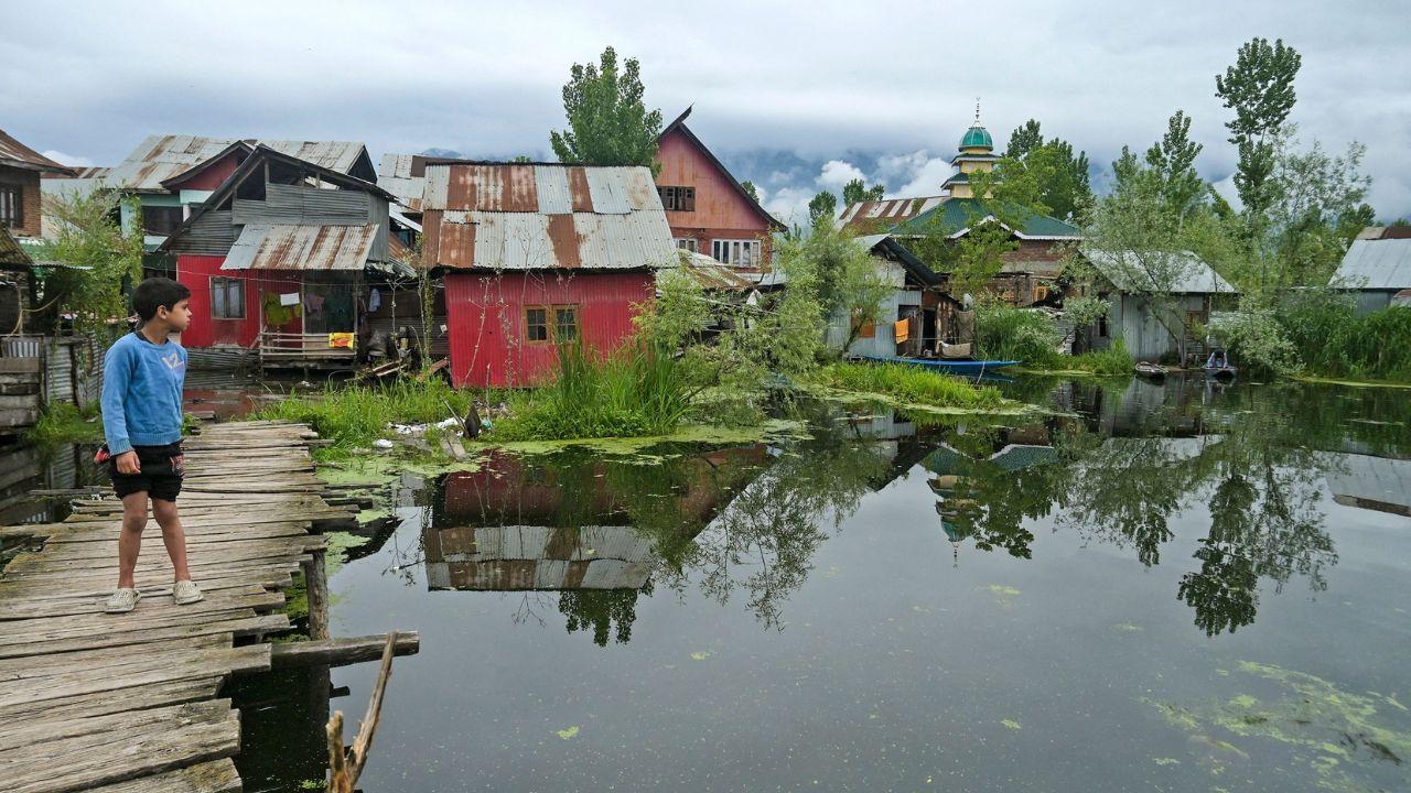 A boy stands on foot bridge outside near his home after water levels rose in the interior of Dal Lake due to heavy rains in Srinagar on April 30, 2024. (Photo by TAUSEEF MUSTAFA / AFP)