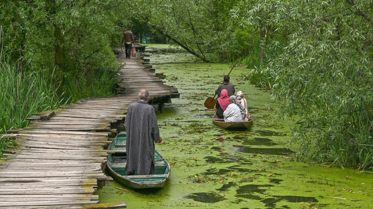 A boatman (right) steers a boat with residents along a canal in the interior of Dal Lake after water levels rose due to heavy rains in Srinagar on April 30, 2024. (Photo by TAUSEEF MUSTAFA / AFP)