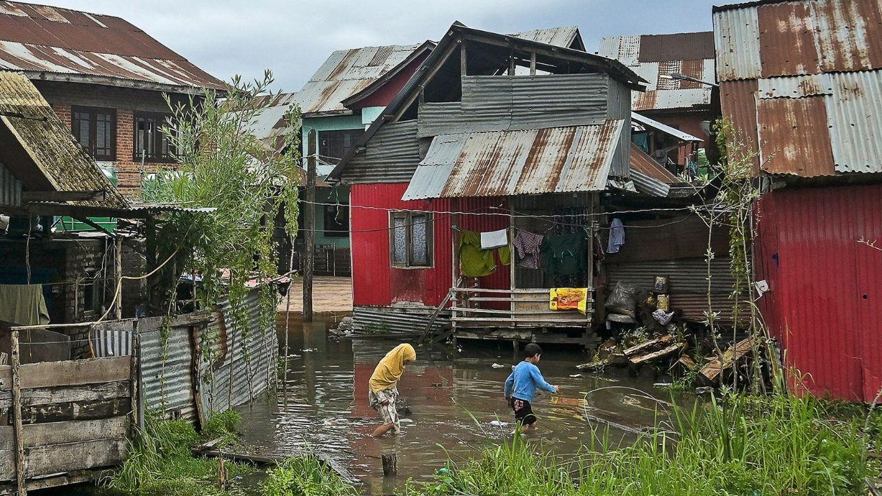 Children wade outside their home in a flooded area after water levels rose in the interior of Dal Lake due to heavy rains in Srinagar on April 30, 2024. (Photo by TAUSEEF MUSTAFA / AFP)