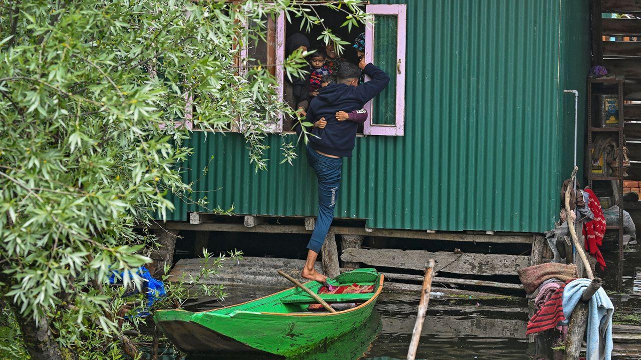 A resident tries to enter his home through a window in a flooded area as water levels rose in the interior of Dal Lake due to heavy rains in Srinagar on April 30, 2024. (Photo by TAUSEEF MUSTAFA / AFP)