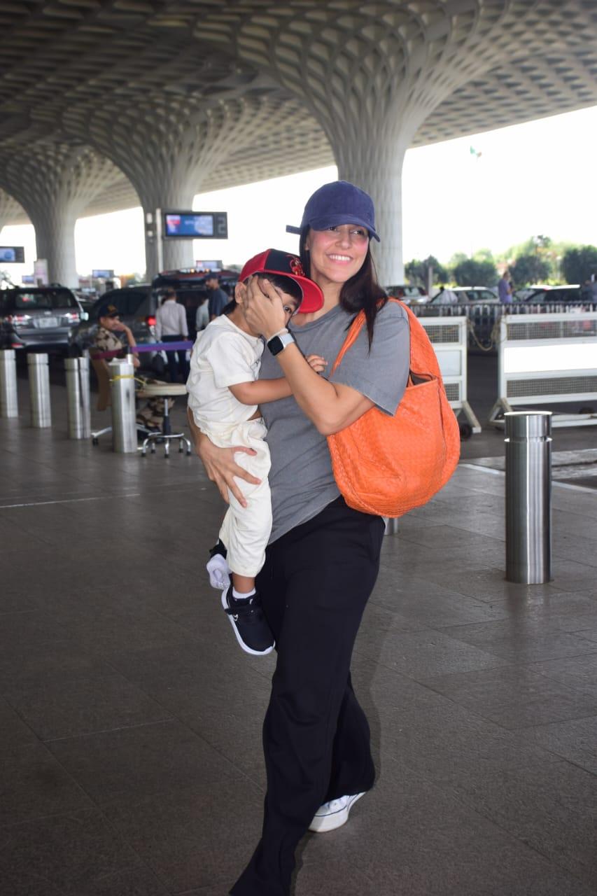Neha Dhupia was spotted with her children at the Mumbai International Airport today. The actress greeted the paparazzi before heading off
