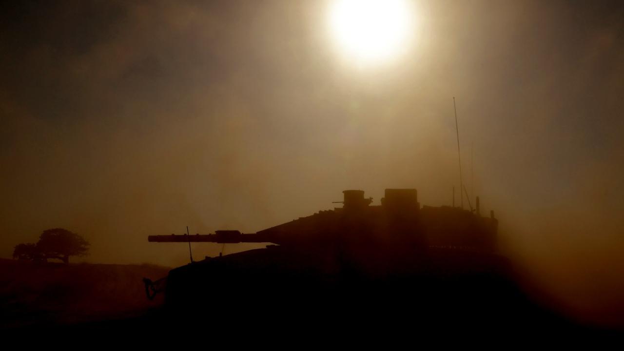 This picture is taken from Israel's southern border with the Gaza Strip shows an Israeli tank silhouetted against the sun as it rolls near the Palestinian territory on April 17, 2024, amid Israel's war in Gaza (Photo by JACK GUEZ/AFP)
