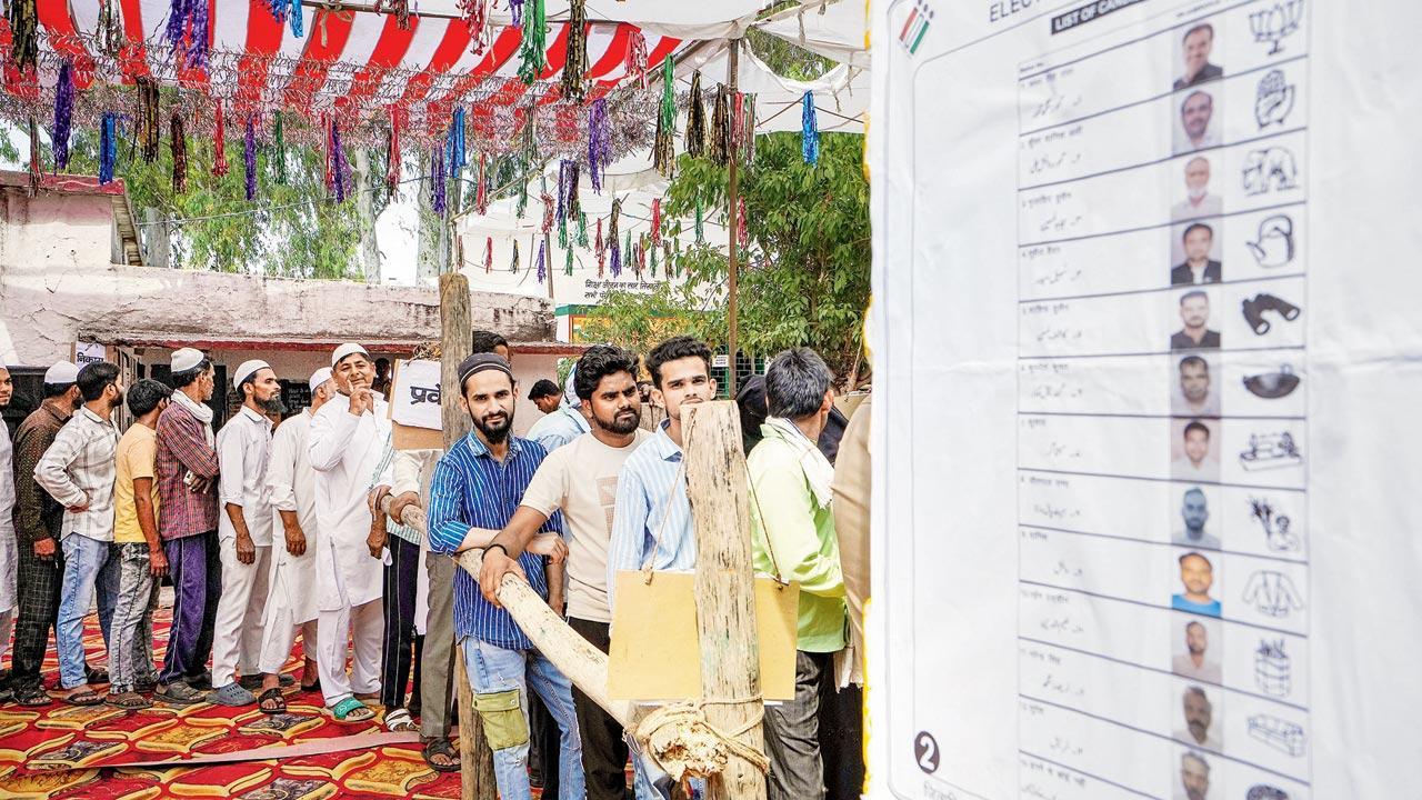 Voters wait in a queue at a polling station. Pic/PTi 