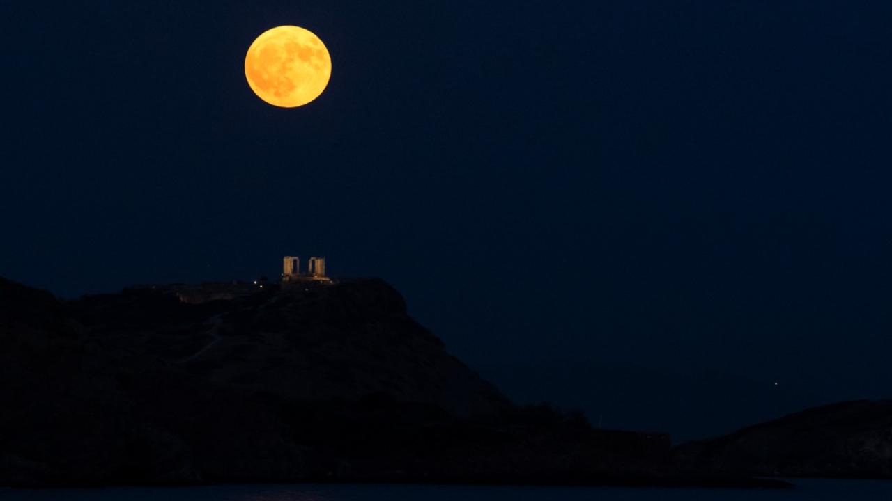 The Super Blue Moon rises behind the ancient temple of Poseidon at Cape Sounion, south of Athens, Greece on August 19, 2024