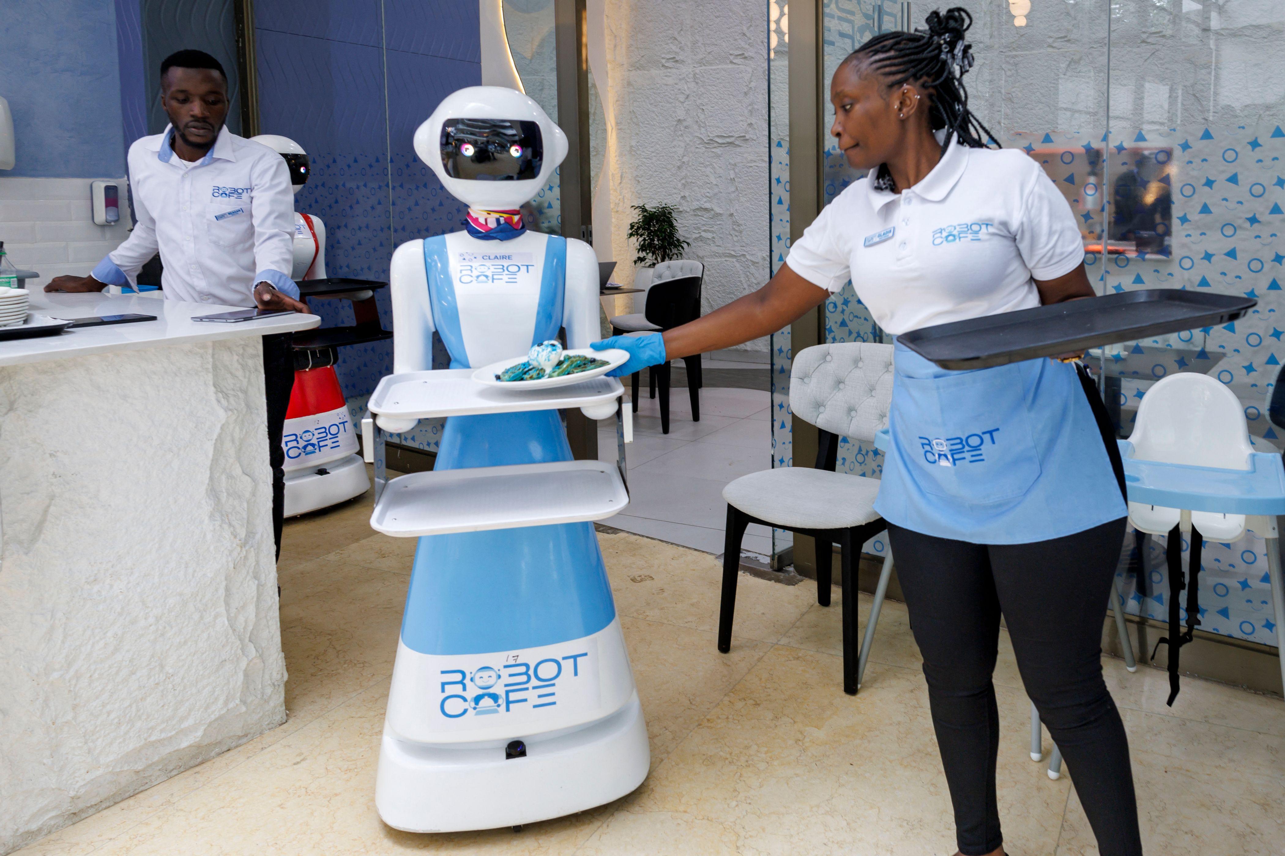 A waitress hands over the platter to the robot to serve it to the customers