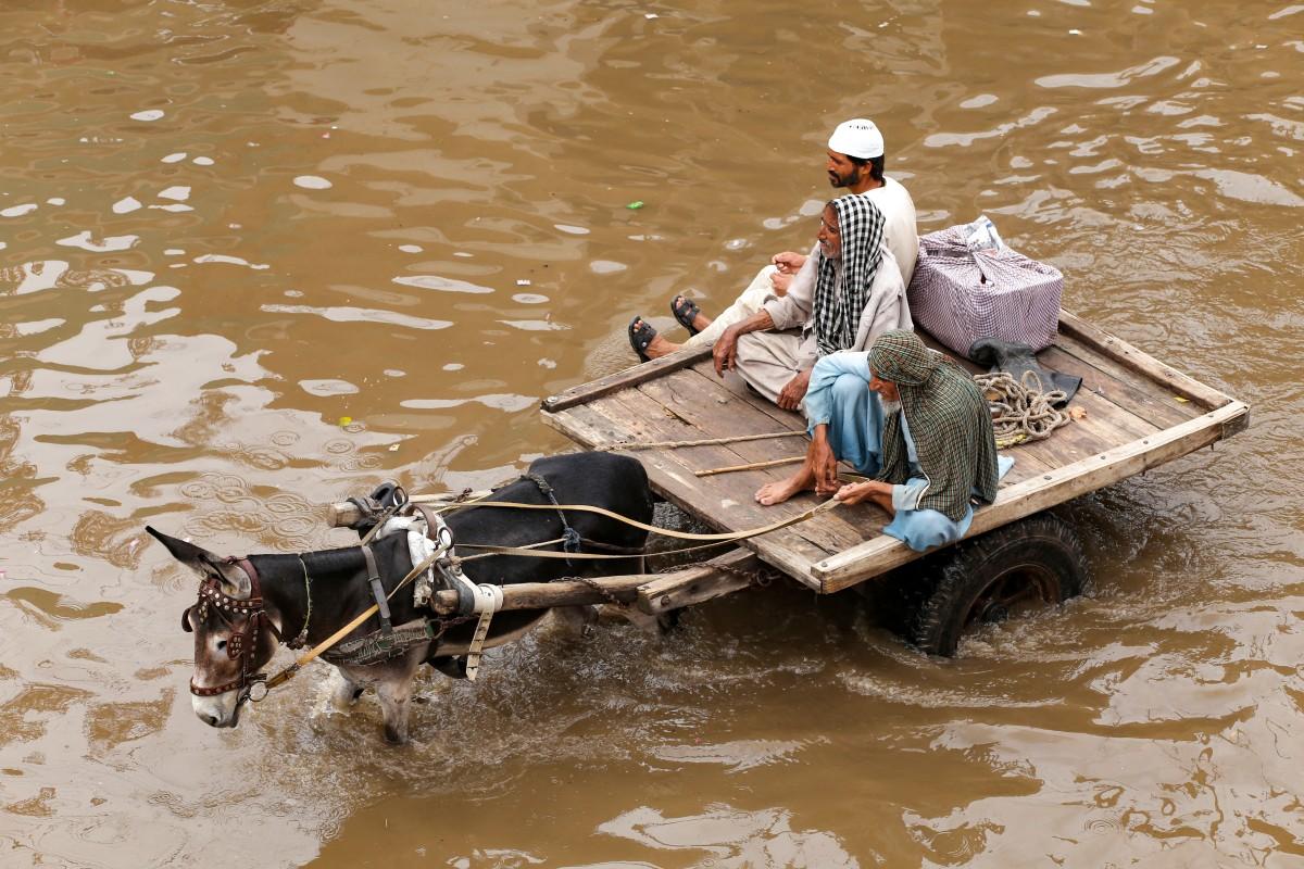 Locals ride a donkey cart through flood waters after heavy rainfall in Multan on Friday 