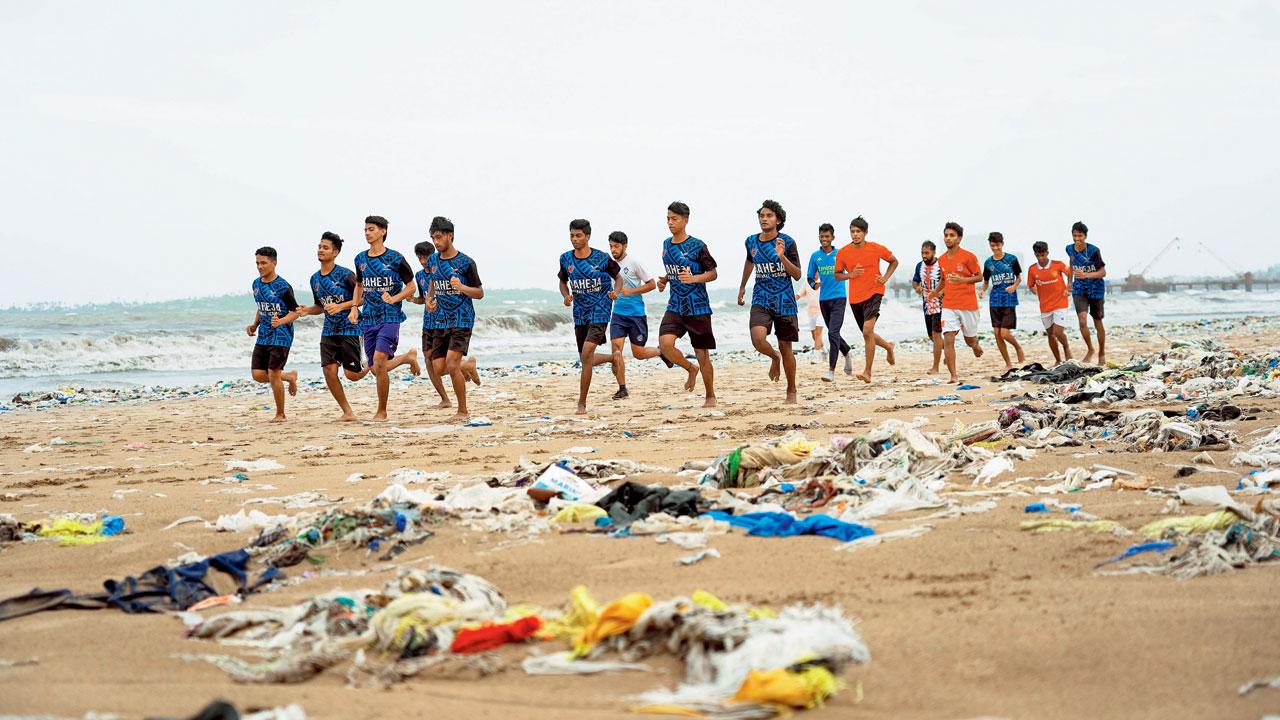 Football players warm up between heaps of garbage at Juhu beach. Pics/Aditi Haralkar