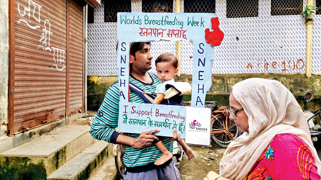 A father and child promote breastfeeding as part of a drive organised by NGO Sneha