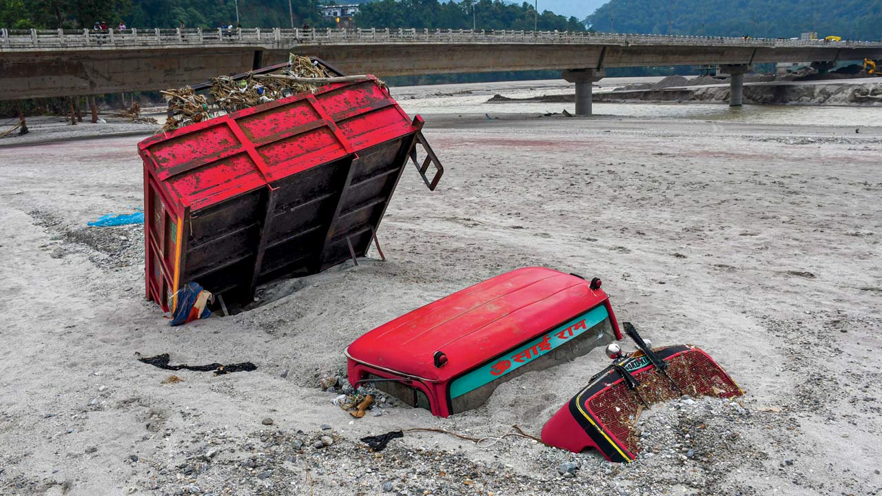 A vehicle seen submerged in mud in the flood-affected area along the Teesta River. A glacial lake in northeast India burst through a dam shortly after midnight of October last year, washing away homes and bridges and forcing thousands to flee. Pic/Getty Images