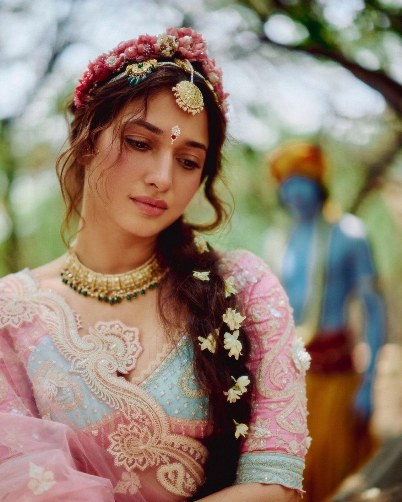 Adorned with a gorgeous maang tikka and a stunning necklace, Tamannaah left her fans in awe. She styled her hair in a messy updo, beautifully decorated with pink and white flowers.