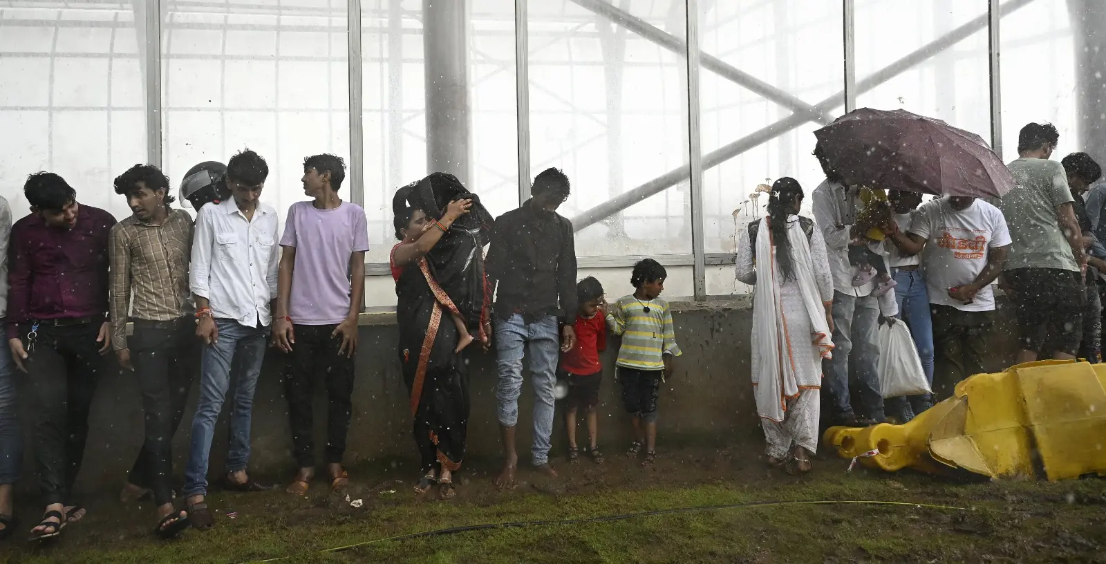 Residents take shelter from the rain under a building in south Mumbai