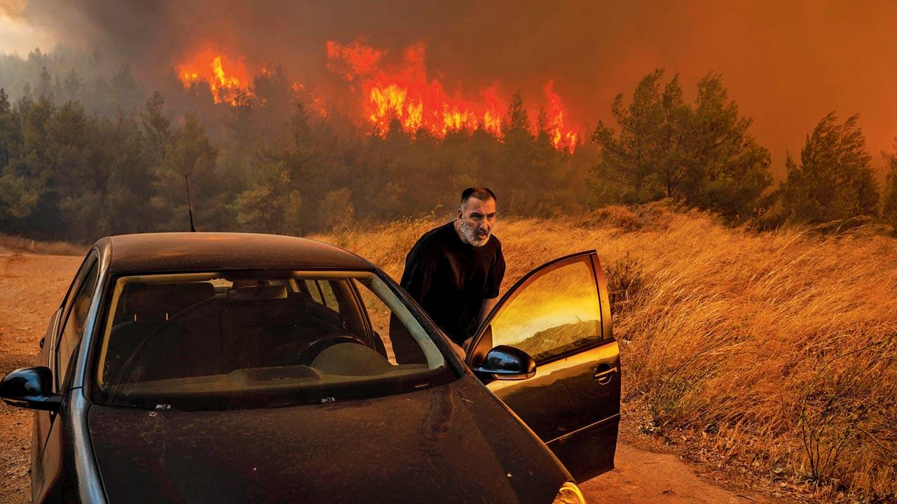 A Dione local gets into his car in front of the flames to evacuate