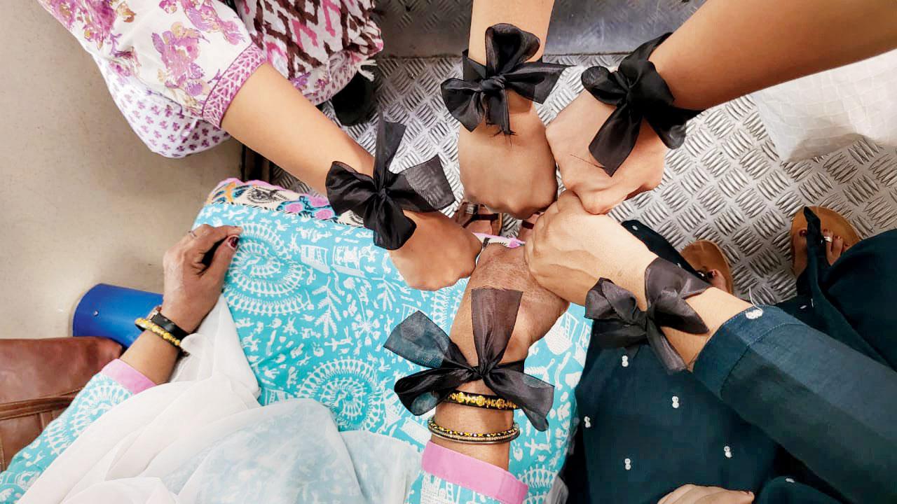 Central Railway commuters show off their black ribbons on a train