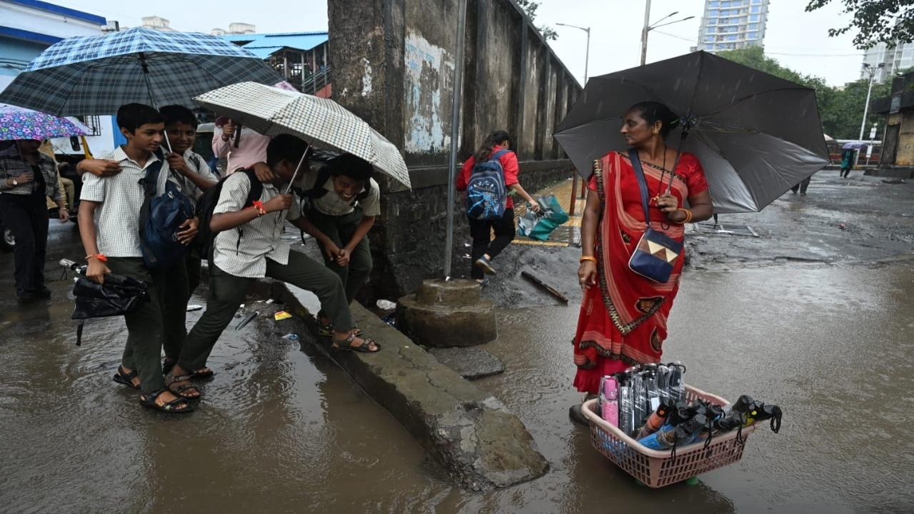 A woman sells umbrella during the heavy rainfall in Goregaon even as kids rush back home from school 