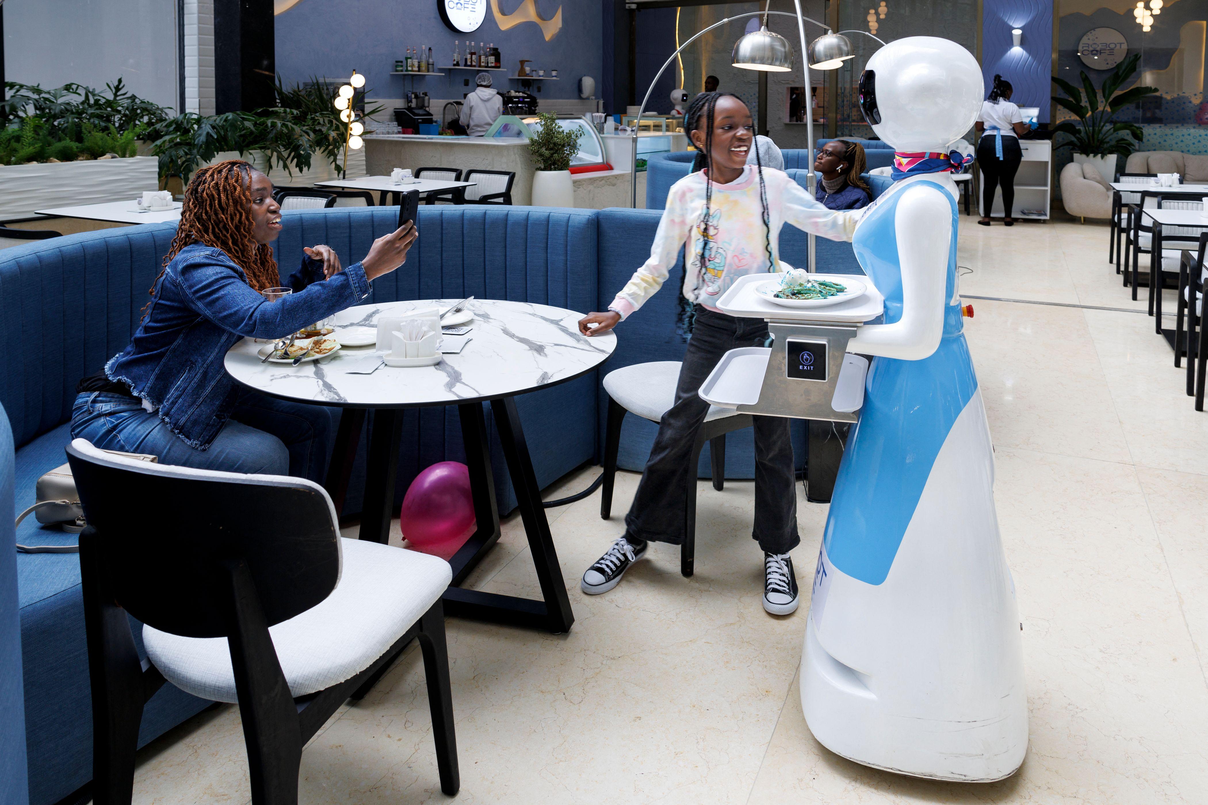 A young patron gets fascinated by the robot that is serving her