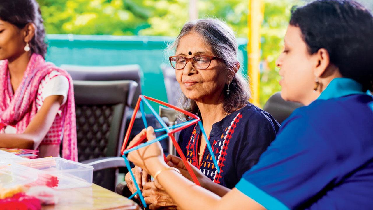 A volunteer helps a senior citizen create a craftwork