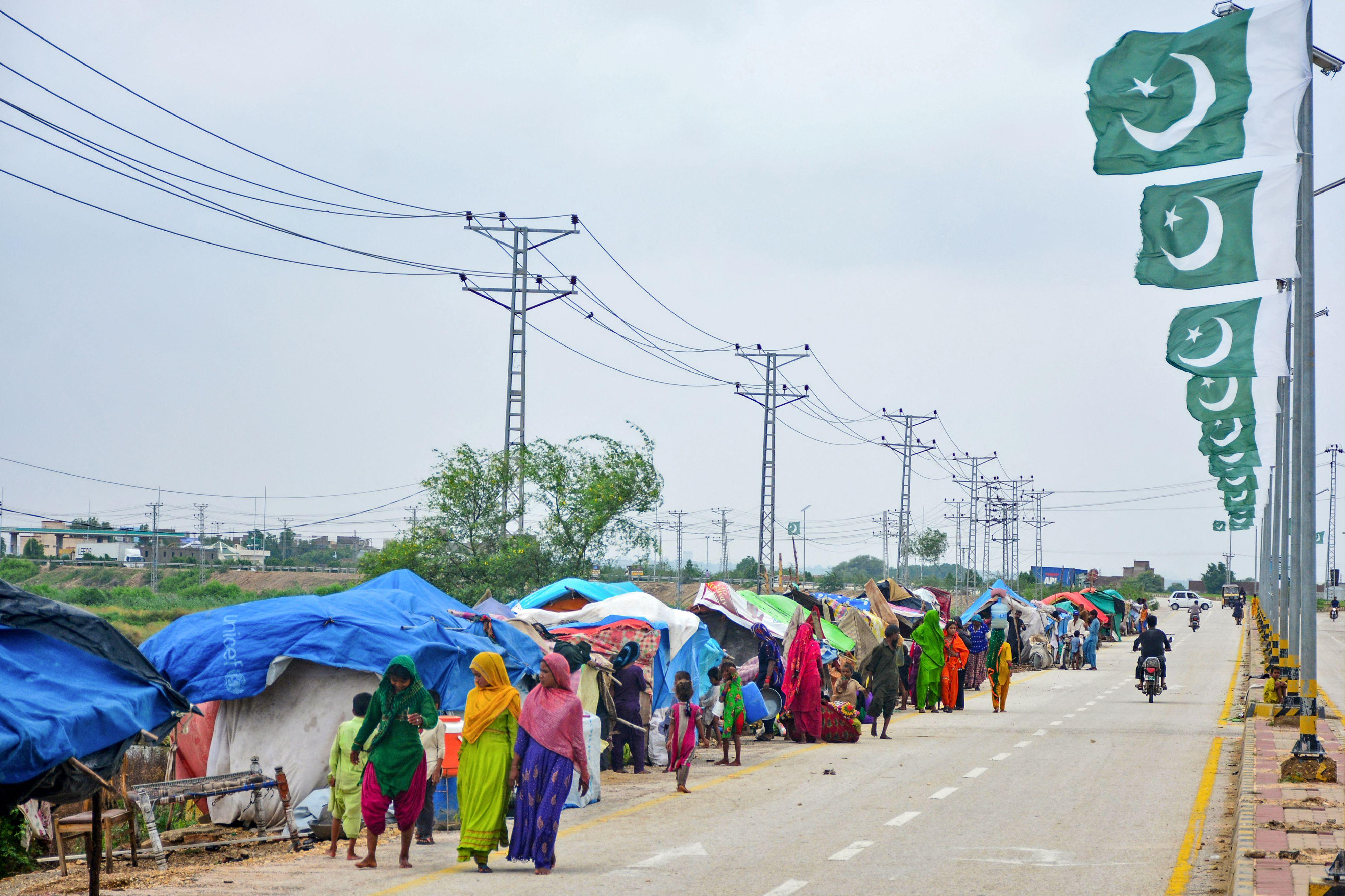 Flood-affected locals walk past their makeshift tents in Sindh region