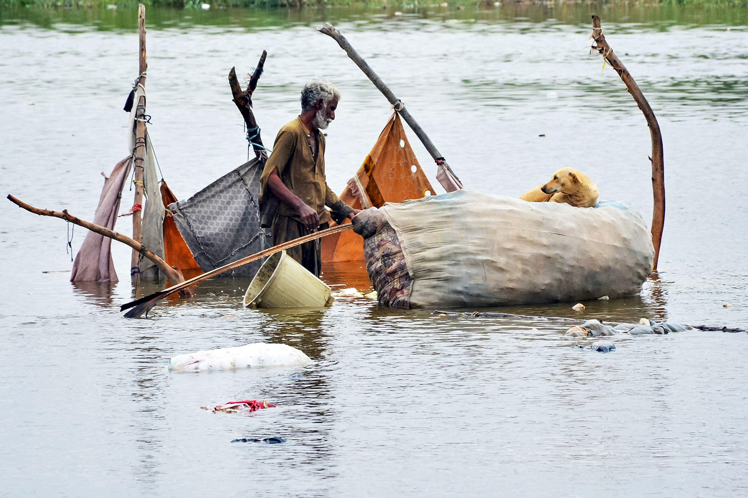 A man gathers belongings from his bamboo tent, partially submerged in flood waters after heavy monsoon rains in Hyderabad, Sindh province