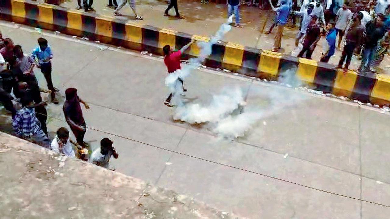 One of the protesters throwing a tear gas canister back towards the cops