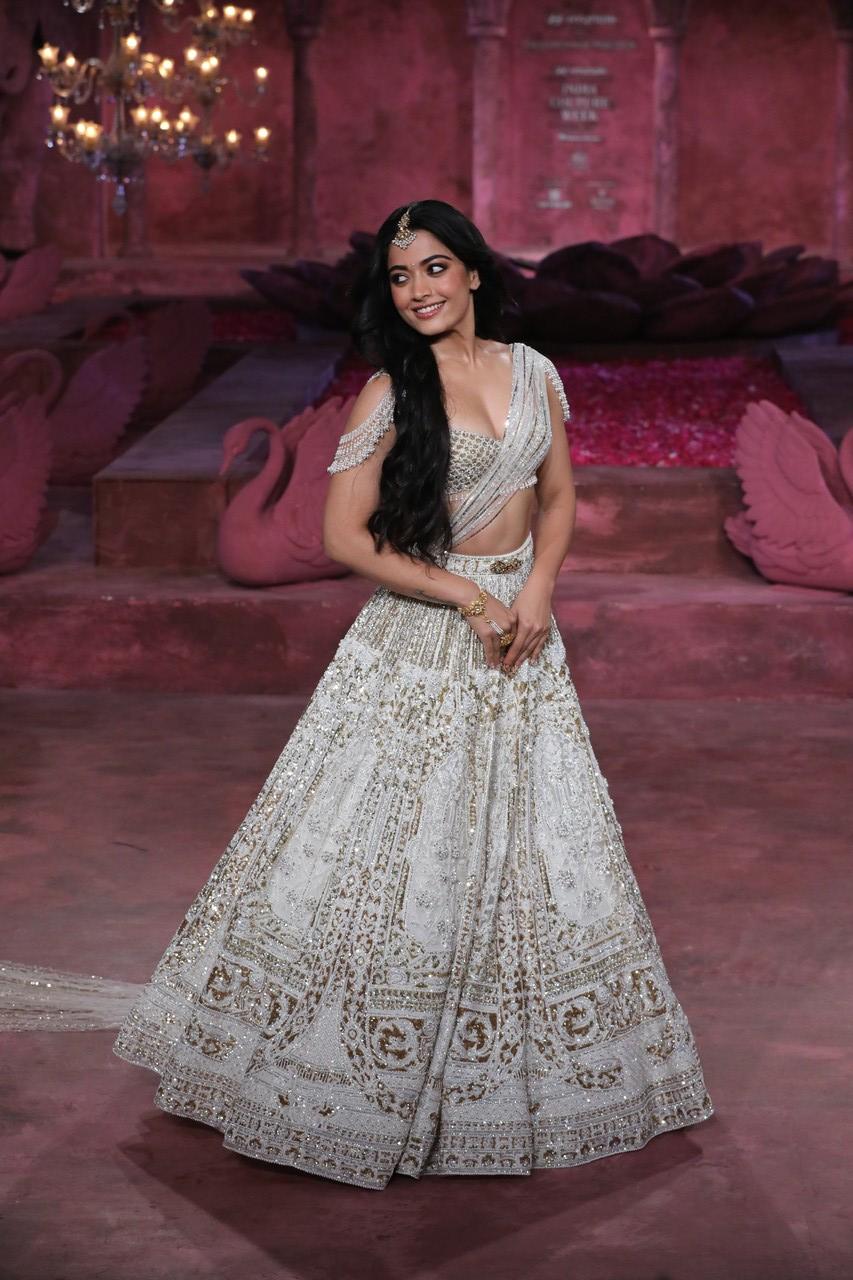 Rashmika turned heads in a stunning ivory lehenga adorned with intricate sequins and beadwork. The lehenga featured a drop-beaded shoulder design on the blouse and was complemented by a gracefully draped long veil.