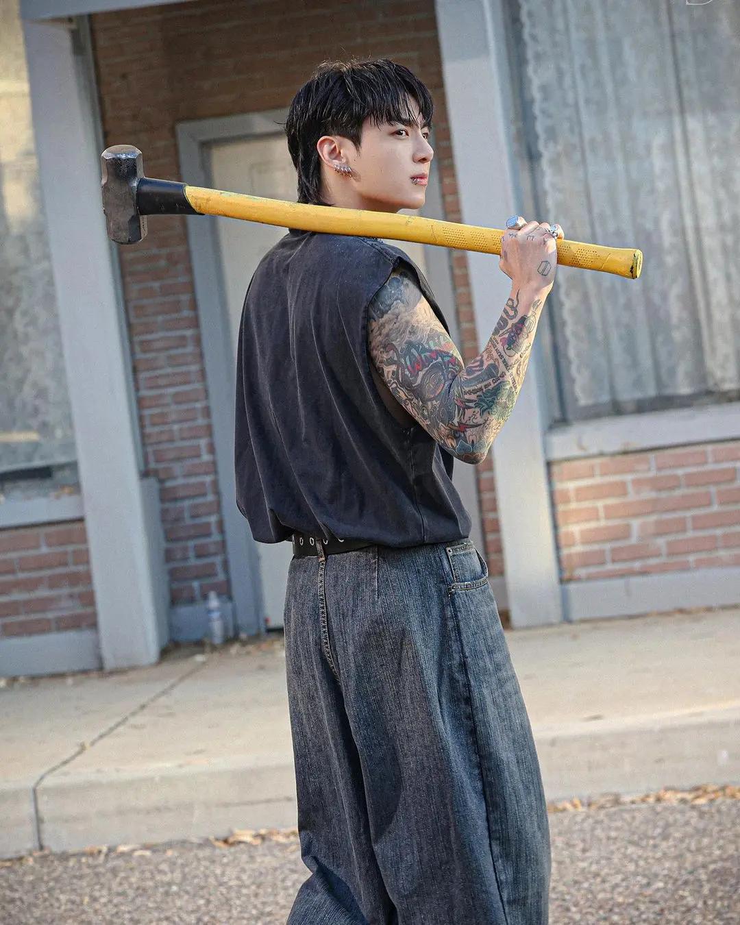 Jungkook is quite the macho man here, posing with a hammer that he used to bust open a fire hydrant in the music video. And, does so, in washed-out jeans and a sleeveless tank top that tucked into his baggy jeans