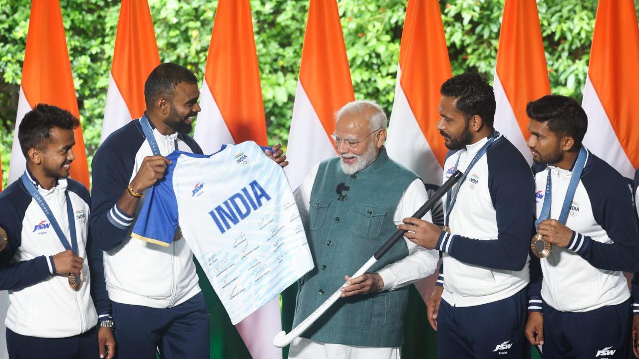 PM Modi being presented a jersey by bronze medallist men`s hockey team members PR Sreejesh, Harmanpreet Singh and others during his interaction with the Indian contingent for Paris Olympics. Pics/PTI