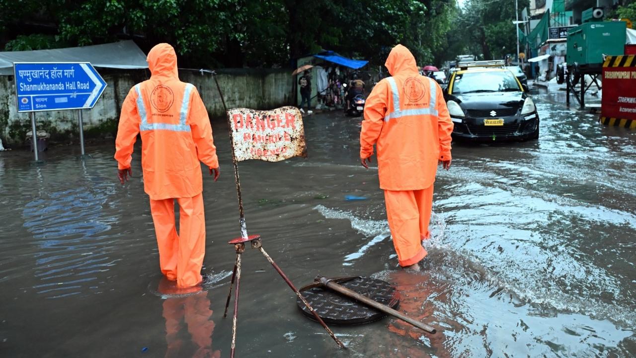 BMC workers opened the manhole lid today near Gandhi Market to alleviate the ankle-deep water accumulated in the area