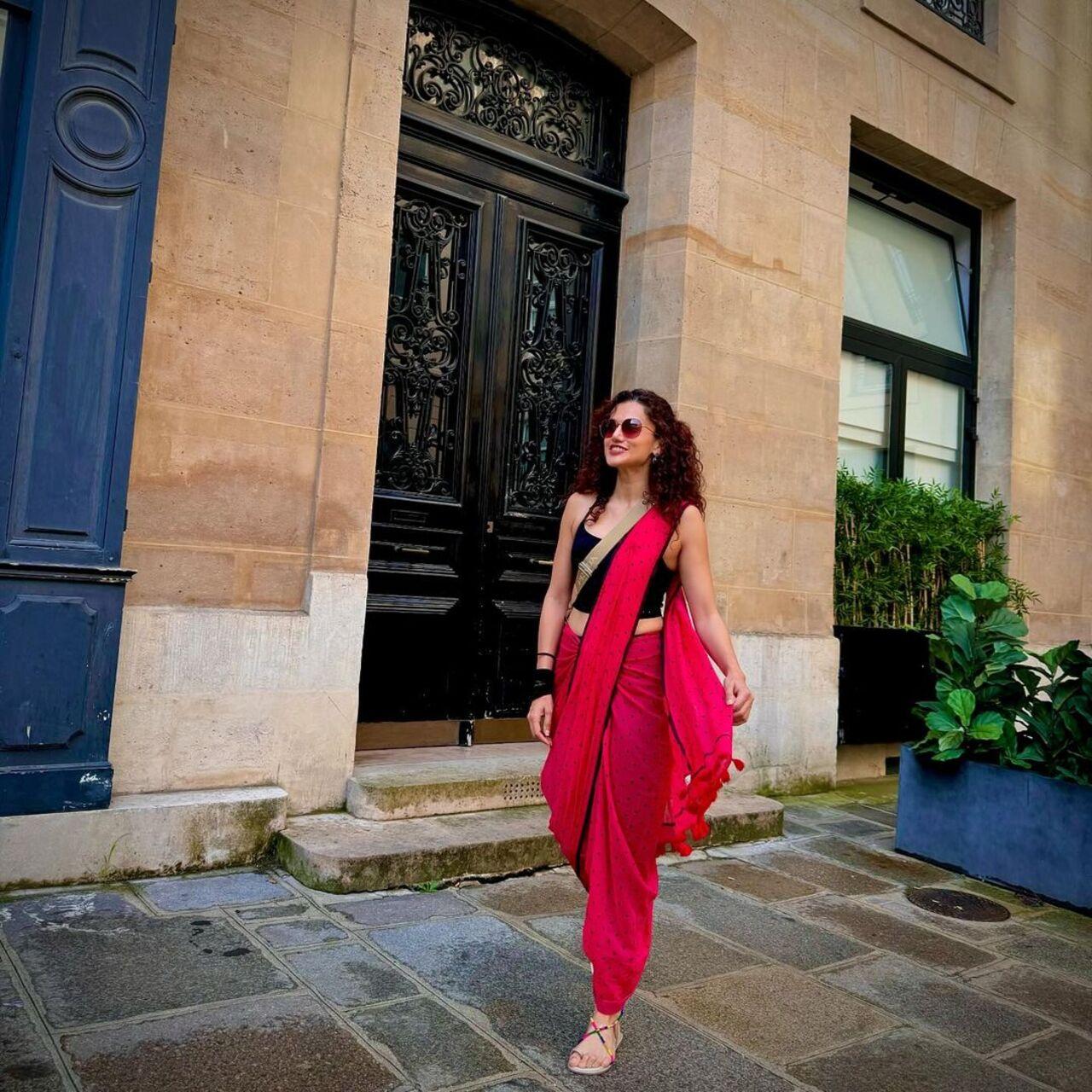 On the second day, she wore a red saree draped around a black co-ord set. She completed her look with strappy sandals, sunglasses, and a sling bag.