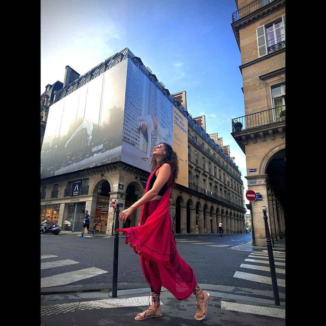 Taapsee Pannu has been experimenting with how she drapes her sarees. On Day 2 in Paris, the actress wore a red saree in dhoti style, pairing it with tie-up sandals.