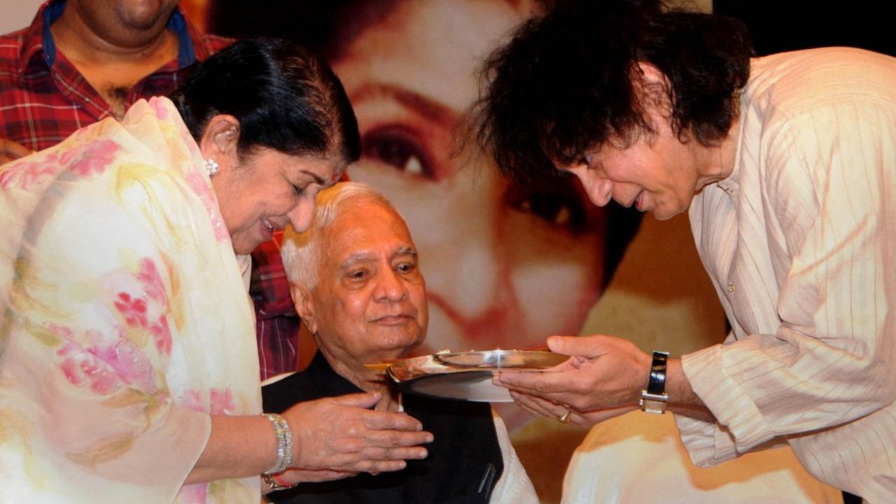 Indian music legend Lata Mangeshkar (L) and Zakir Hussain greet each other during the '72nd Master Deenanath Mangeshkar Awards' in Mumbai on late April 24, 2014