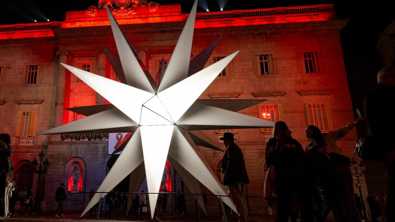 Pedestrians look at a giant star during Christmas illuminations in a street of Barcelona