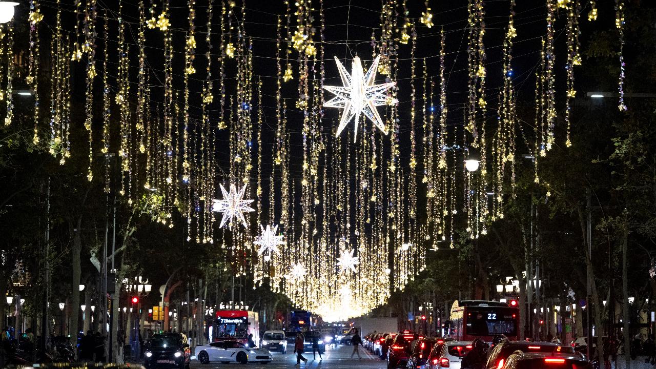 Cars pass under Christmas illuminations in a street of Barcelona