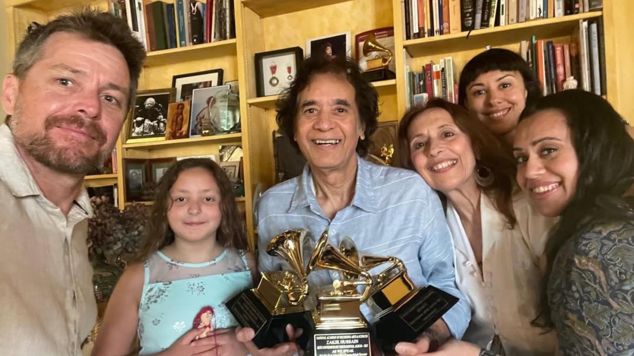 Zakir Hussain is surrounded by his family as he poses with the Grammys