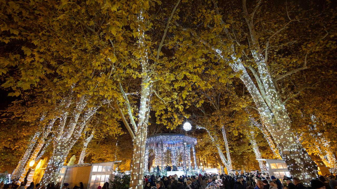 Attendees stand beside an illuminated Art Pavilion at the opening of the Advent Zagreb Christmas market event in Zagreb, Croatia