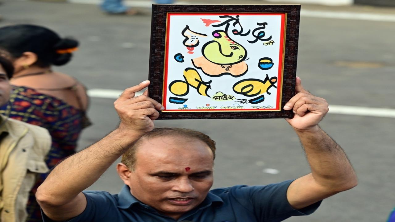 A man holds a Ganpati painting with PM Narendra Modi's name