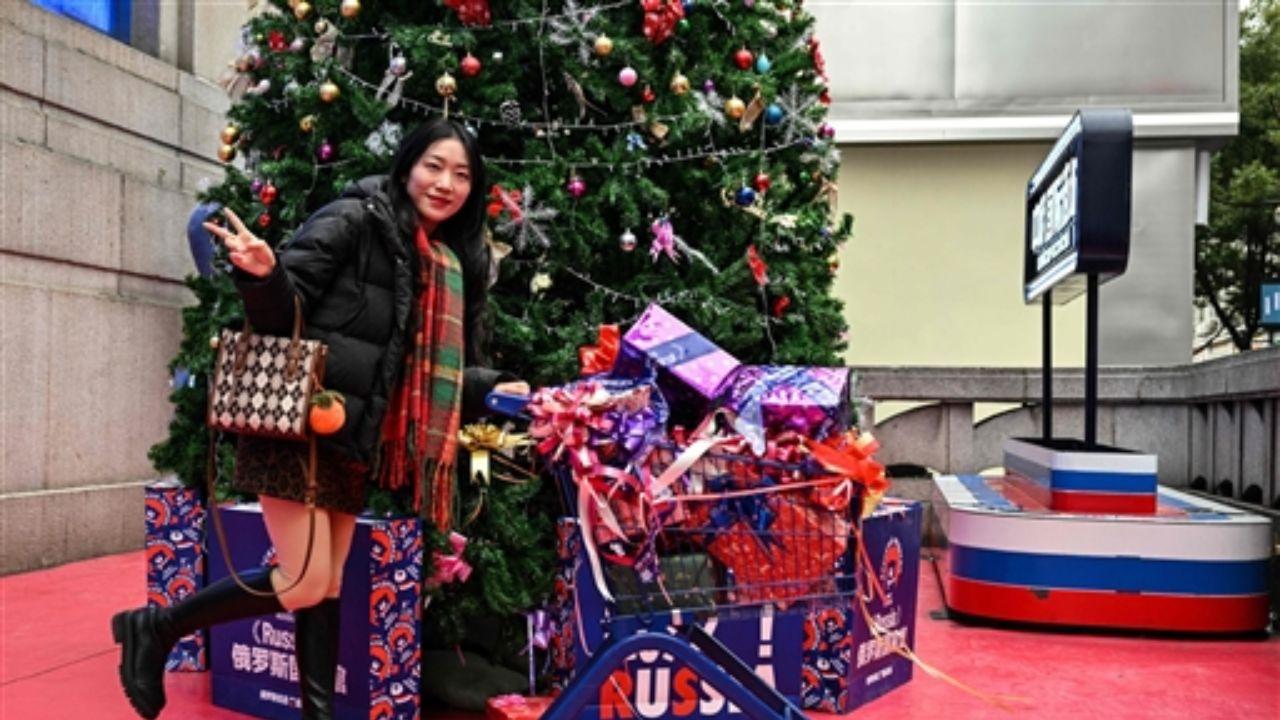 A woman poses for pictures next to a Christmas tree in a shop selling Russian products in Wuhan, in China's central Hubei province