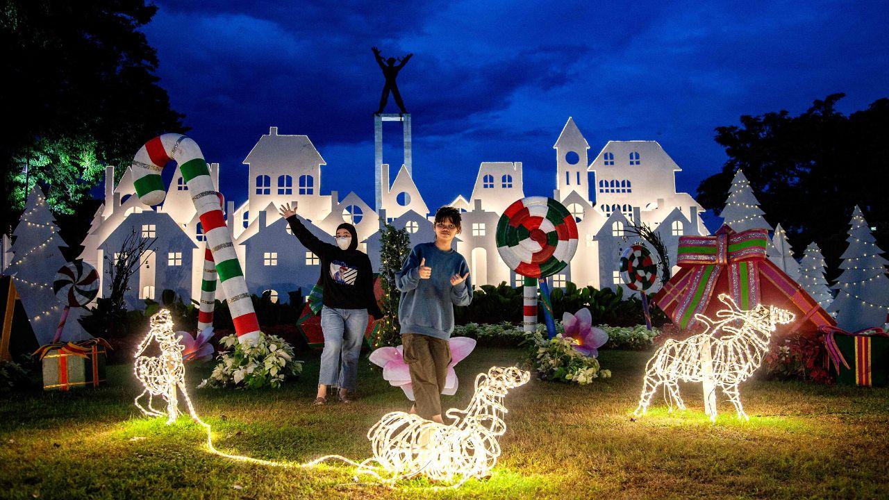 People take selfies with Christmas decorations at the Lapangan Banteng Park near a church, on the eve of Christmas Day celebrations in Jakarta, Indonesia