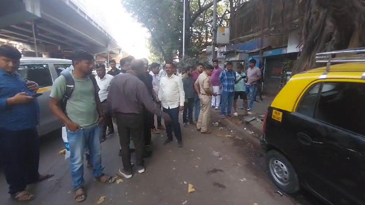 Onlookers gather near the accident site, where the taxi came to a halt after crashing into the food stall