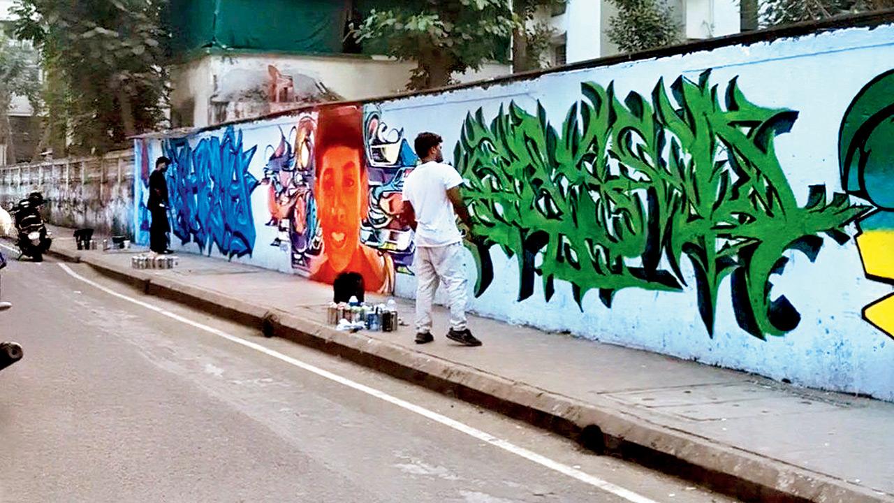 Artists work on the stretch of the wall in Airoli