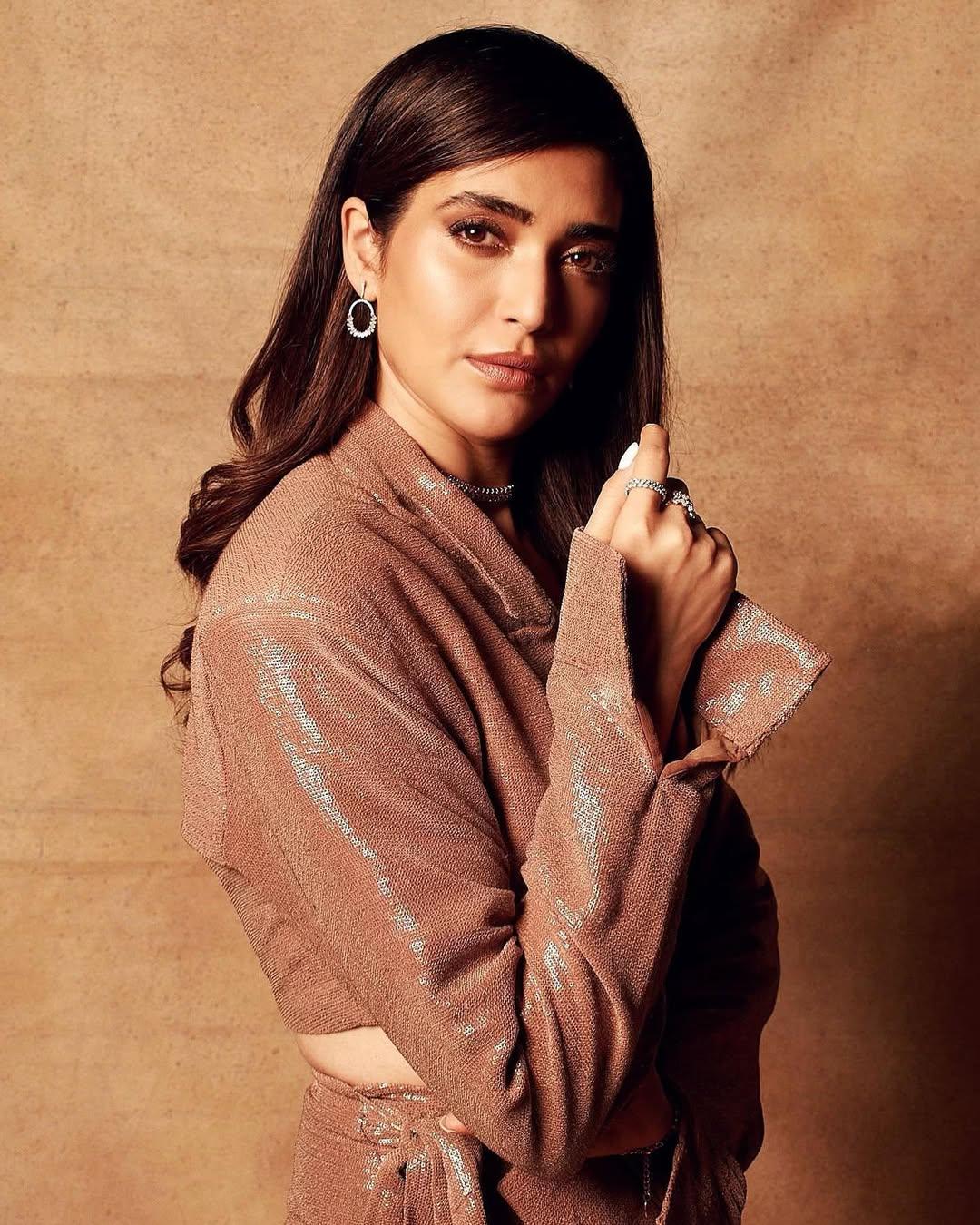 The crop top featured a V-neckline. For her hair, she kept an easy hairstyle, and her shiny makeup stole our hearts. For accessories, she chose a chic neckpiece with multiple rings and earrings