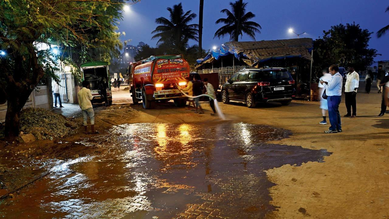 BMC staffers spray water outside the Otters Club in Bandra West as part of the civic body’s dust-mitigation measures on Monday. Pic/Sayyed Sameer Abedi