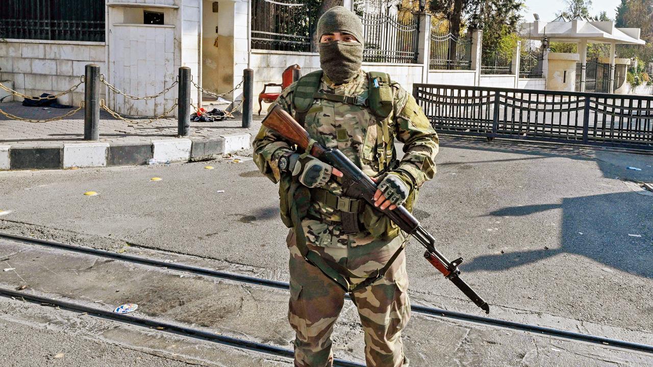 An anti-government fighter stands guard outside the Defence Ministry building in Damascus. Pic/AP