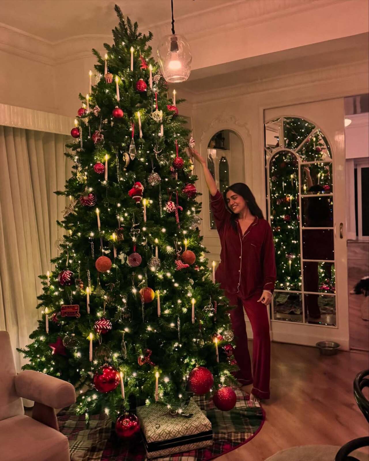 The actress set up a massive Christmas tree and posed beside it on the eve of the holiday in a red pajama