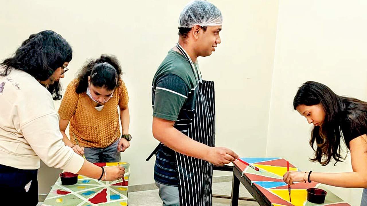The team paints table tops with vibrant colours at the new space in Vile Parle 