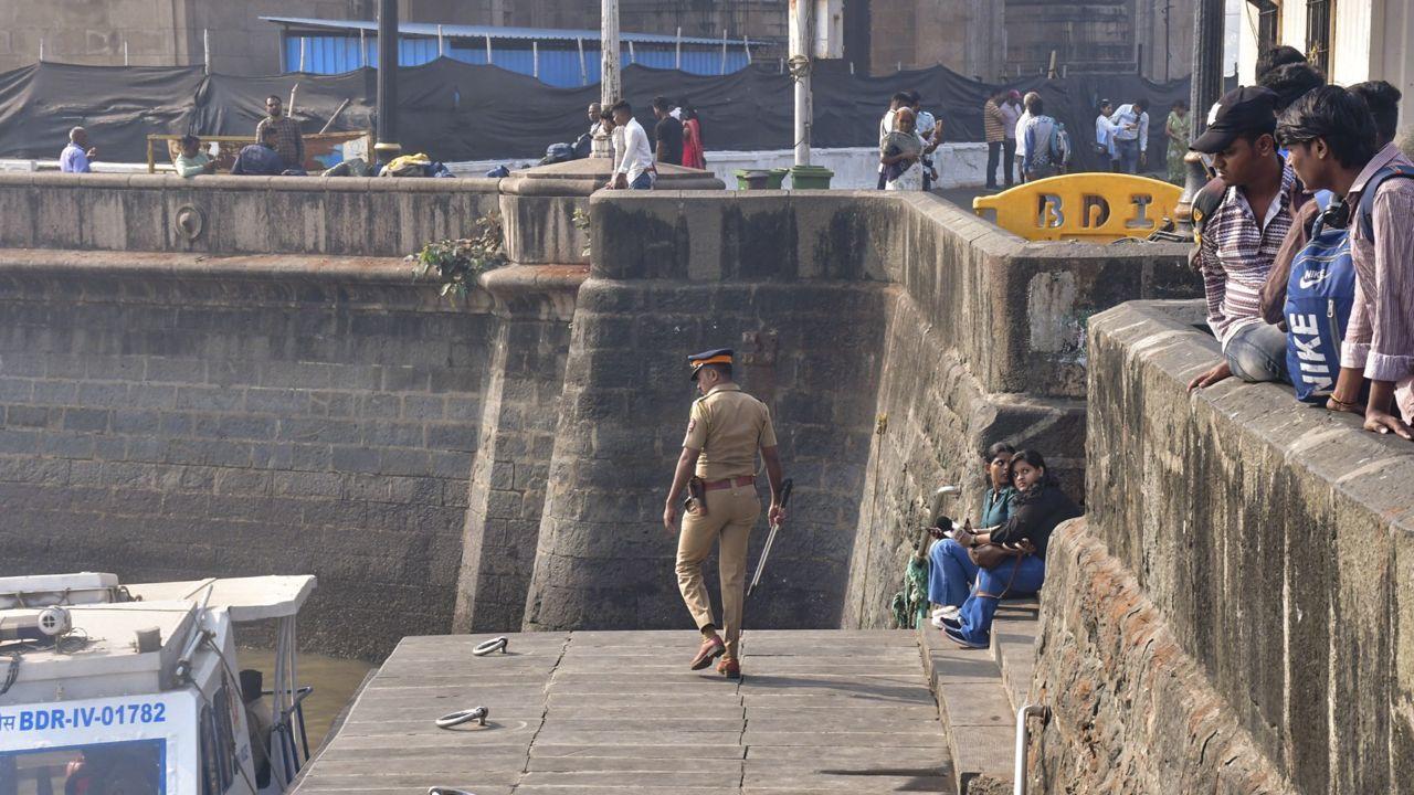 Two passengers, a man and a child, were still missing a day after the incident, police said on Thursday. (In Pic: A police personnel keeps vigil at the coast as people look on following an incident)