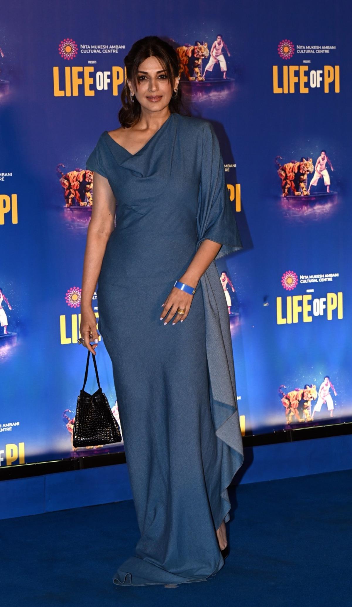 Sonali Bendre was papped at NMACC's musical premiere in a grey and blue asymmetrical gown and she paired the outfit with a black handbag